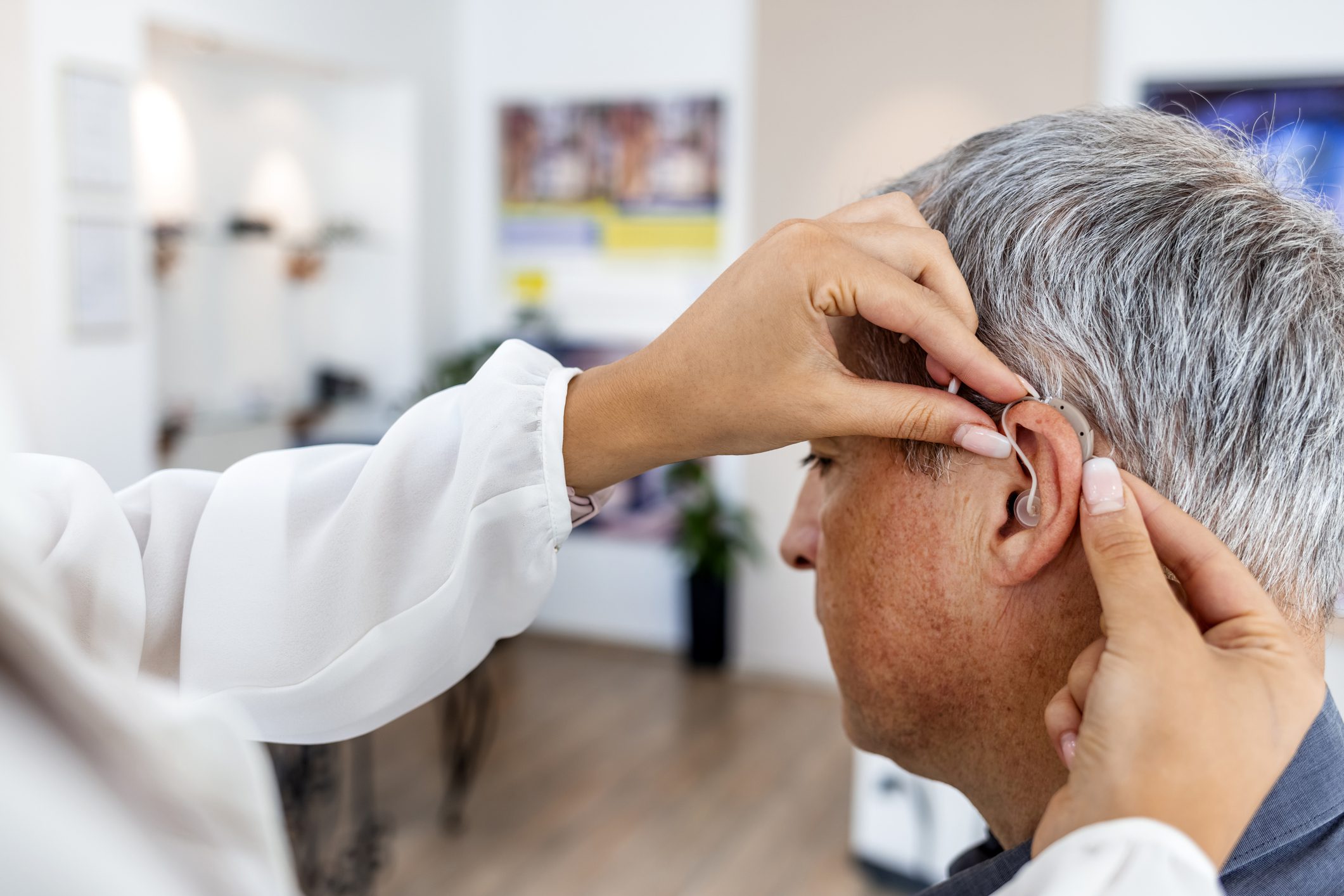 Female doctor fitting a male patient with a hearing aid